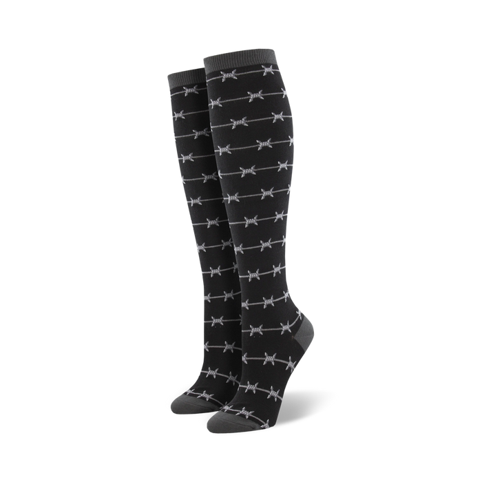 Pair of black knee-high socks with a repeating grey barbed wire pattern. The socks have a dark grey cuff. }}