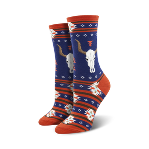 Close-up view of a pair of navy blue and orange crew socks with the same longhorn skull and southwestern pattern design.