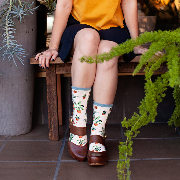 Lifestyle shot of a woman in a black skirt and Home Grown socks, standing in a plant shop.