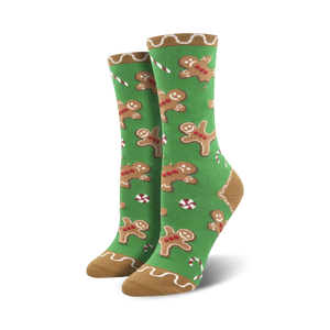 Pair of crew socks with a festive design. Green background with gingerbread men and candy canes. Tan cuff.