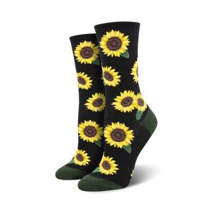 A pair of crew socks with a sunflower pattern. The socks are black with yellow sunflowers and green leaves, and have dark green cuffs.
