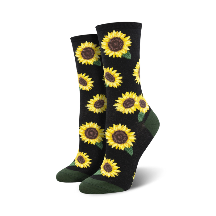 A pair of crew socks with a sunflower pattern. The socks are black with yellow sunflowers and green leaves, and have dark green cuffs.