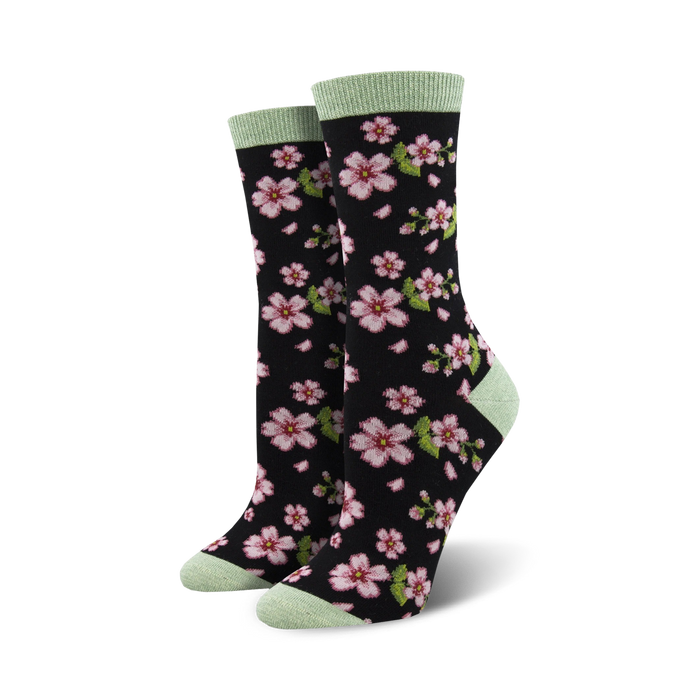 Pair of women's crew socks in black with pink cherry blossom design and light green cuffs.