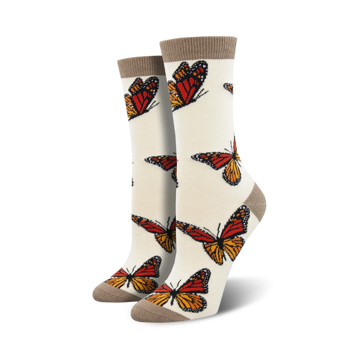 Pair of cream women's crew socks adorned with orange and brown monarch butterfly prints.  Features a subtle taupe cuff.