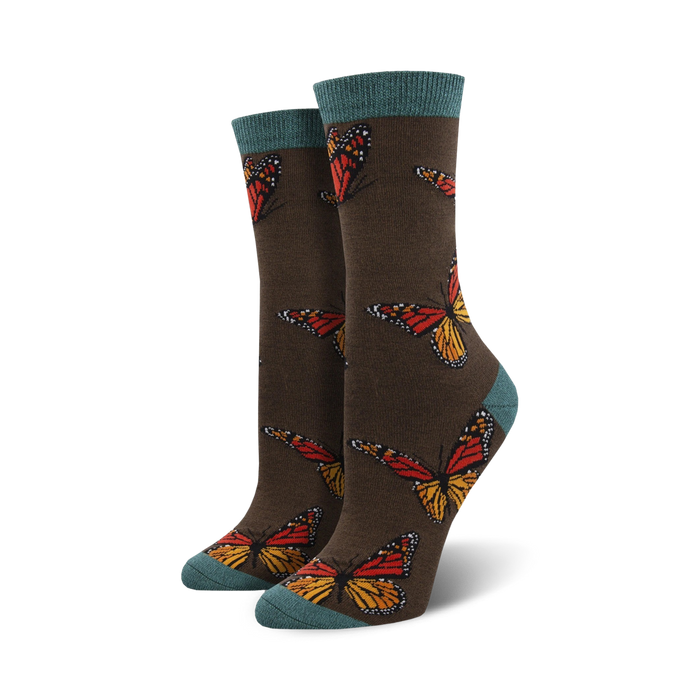 Close-up of a pair of dark brown crew socks with teal cuffs, showcasing the monarch butterfly design.