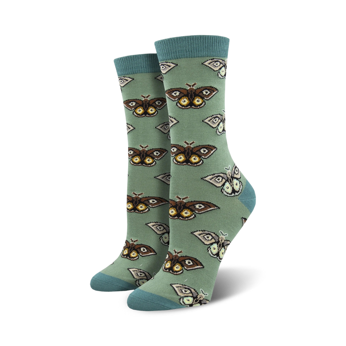 Close-up of a pair of sage green crew socks with a repeating pattern of brown and cream moths. Soft bamboo fabric.