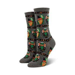 Pair of crew socks in grey and orange, showcasing a repeating pattern of pixel art witches and owls with stars and crescent moons.