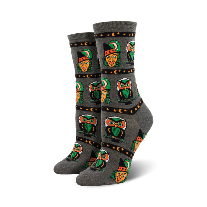 Pair of crew socks in grey and orange, showcasing a repeating pattern of pixel art witches and owls with stars and crescent moons.