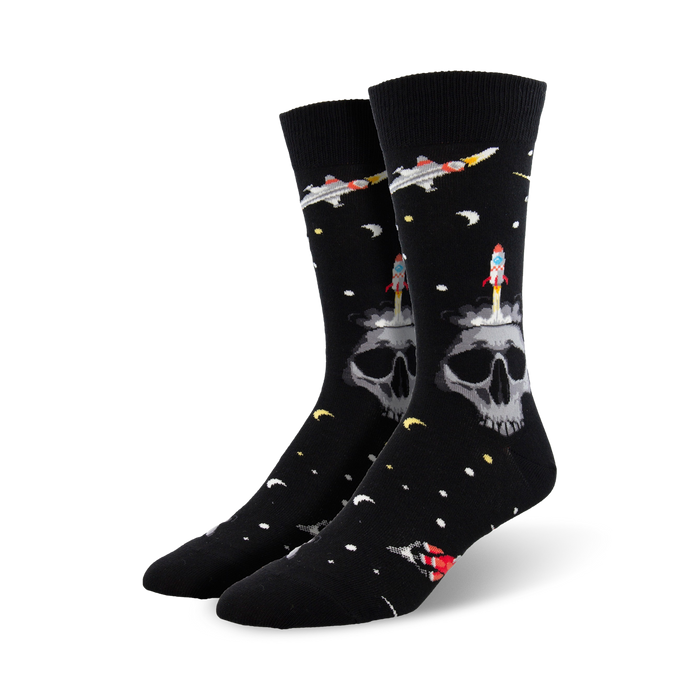 Pair of black crew socks with a skull, rocket, and spaceship design against a space-themed background. }}