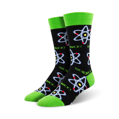 A pair of crew socks with a black background, lime green cuffs, and repeating atom designs in blue, red, and yellow.