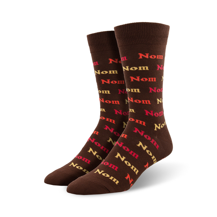 Pair of brown crew socks with a repeating pattern of the word 'nom' in orange, red, and beige. }}