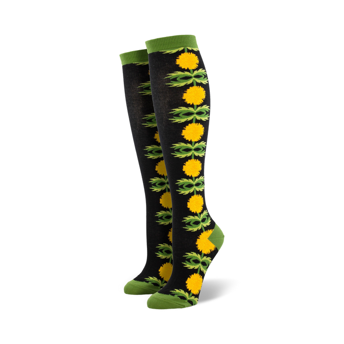 Pair of black knee-high socks with a vertical pattern of yellow dandelions and green leaves. }}