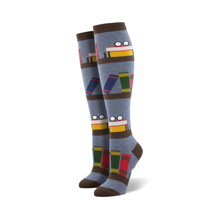 Pair of blue knee-high socks with a bookshelf design. Books, glasses, and brown stripes are featured on a grey-blue background.