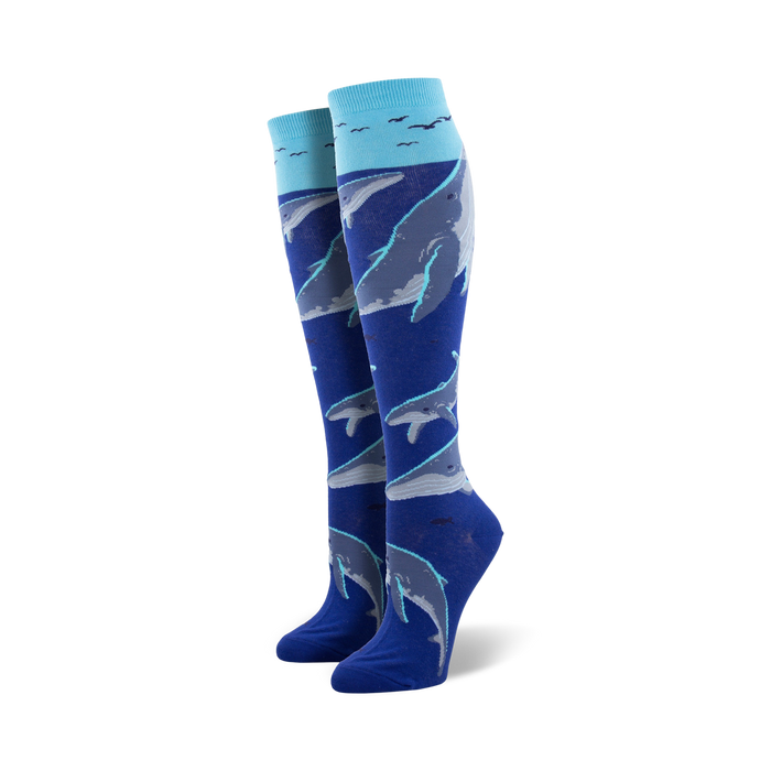 Pair of women's knee-high socks in blue and teal, adorned with a pattern of whales swimming underwater, accented with small birds near the top. }}