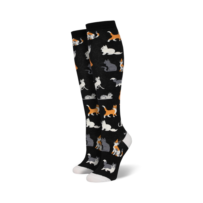 Pair of black knee-high socks with a pattern of cute cats in orange, grey, and white. A fun and whimsical design. }}