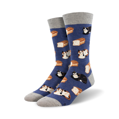 A pair of crew socks in blue with a pattern of cats and bread loaves. The cats are calico and black. The socks have gray cuffs.