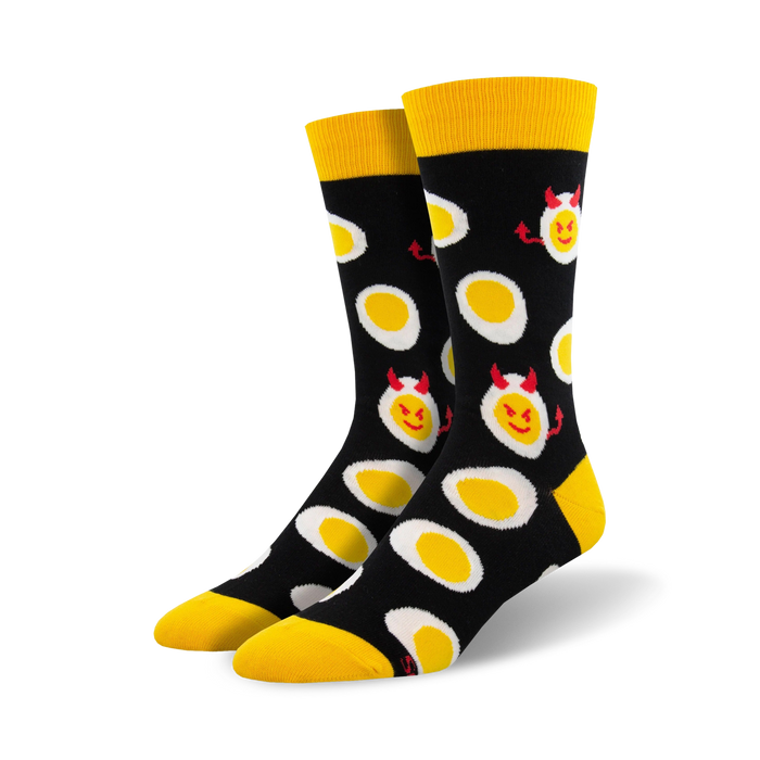 A pair of black crew socks with a fun pattern of yellow deviled eggs. The eggs have small red devil horns and mischievous smiles. }}