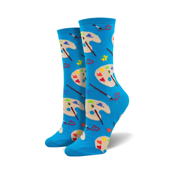 A pair of women's crew socks in bright blue. The design showcases colorful artist palettes, paintbrushes, and small hearts. }}