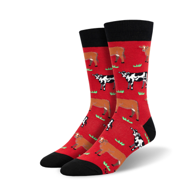Pair of crew socks; red and black with repeating pattern of brown and black cows in a grassy field.