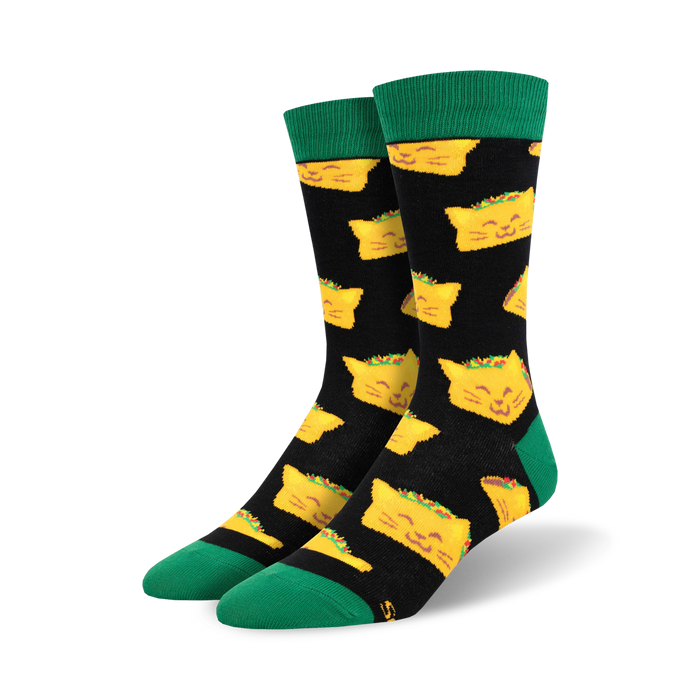 Pair of crew socks with a black background and a repeating pattern of yellow cat-shaped tacos. Green cuffs. }}