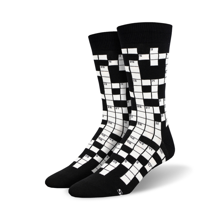 Pair of black and white crew socks featuring a crossword puzzle design. Numbers are visible in the grid.