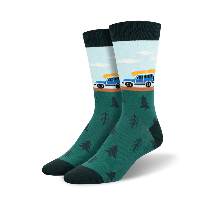 mens dark green crew socks with a pattern of pine trees and a blue pickup truck hauling a yellow canoe on a road leading up a hill.    }}