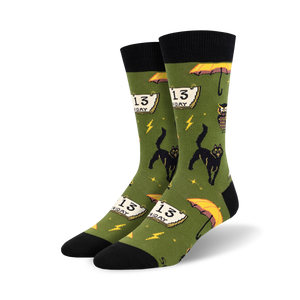 Pair of crew socks in olive green and orange, showcasing a fun, pixelated design of black cats, Friday the 13th calendars, and yellow umbrellas.