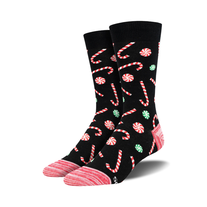 Pair of crew socks with a black background, adorned with red and white candy canes and green and red peppermint swirls. }}