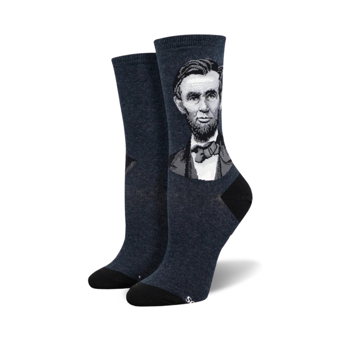 A pair of women's crew socks in dark blue featuring a grayscale portrait of Abraham Lincoln. The socks have black heels and toes. }}