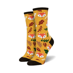 Pair of crew socks in mustard yellow. Features repeating pattern of cute fox faces and autumn leaves.