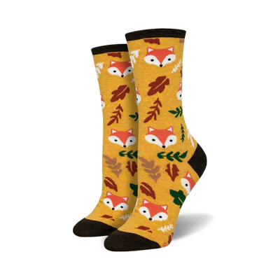 Pair of crew socks in mustard yellow. Features repeating pattern of cute fox faces and autumn leaves.