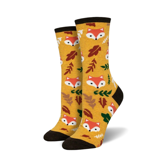 Pair of crew socks in mustard yellow. Features repeating pattern of cute fox faces and autumn leaves.