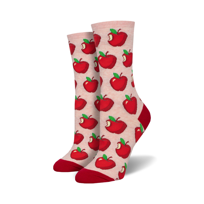 Close-up of a pair of blush pink crew socks with a red apple pattern and red cuffs.