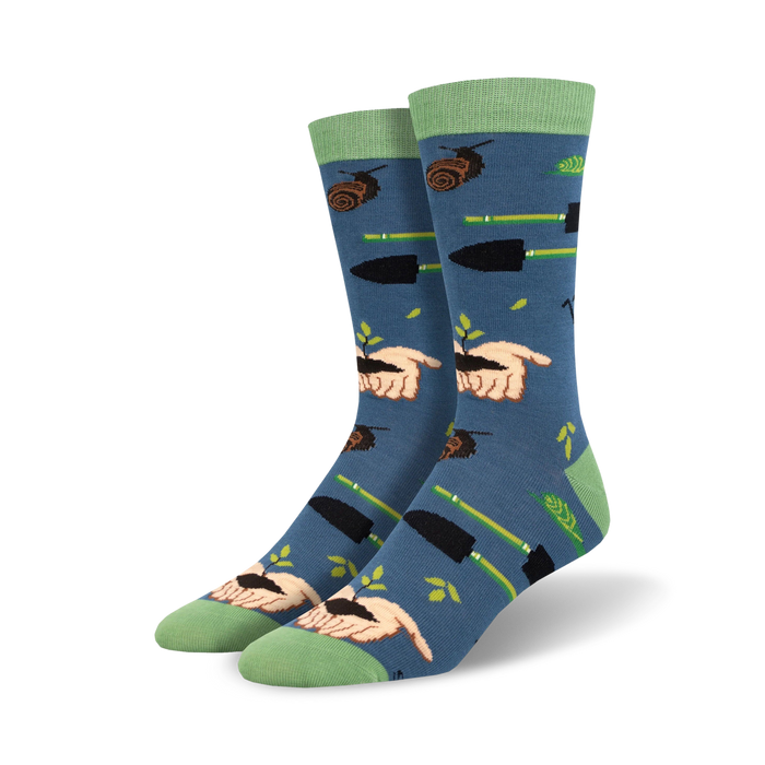 Pair of crew socks in blue with a gardening theme.  Features hands planting seeds, gardening tools, and snails on a soft blue background. Green accents on cuffs. }}