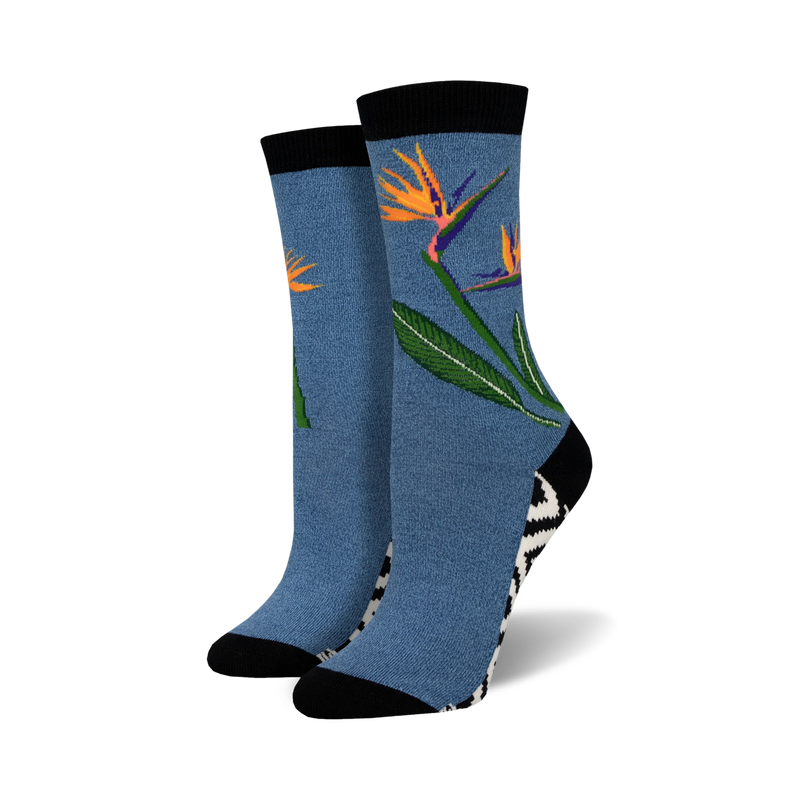 Pair of crew socks in blue featuring a bird-of-paradise flower design. Black and white zig-zag pattern at the ankle. Soft bamboo.