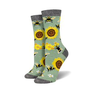 Pair of crew socks with bees, sunflowers, and honeycomb pattern on a sage green background.  Black and grey top cuff.