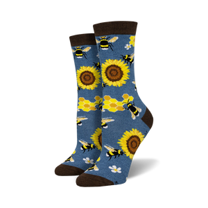 A pair of crew socks with bees, sunflowers and honeycomb pattern on a denim blue background. Brown top cuff.