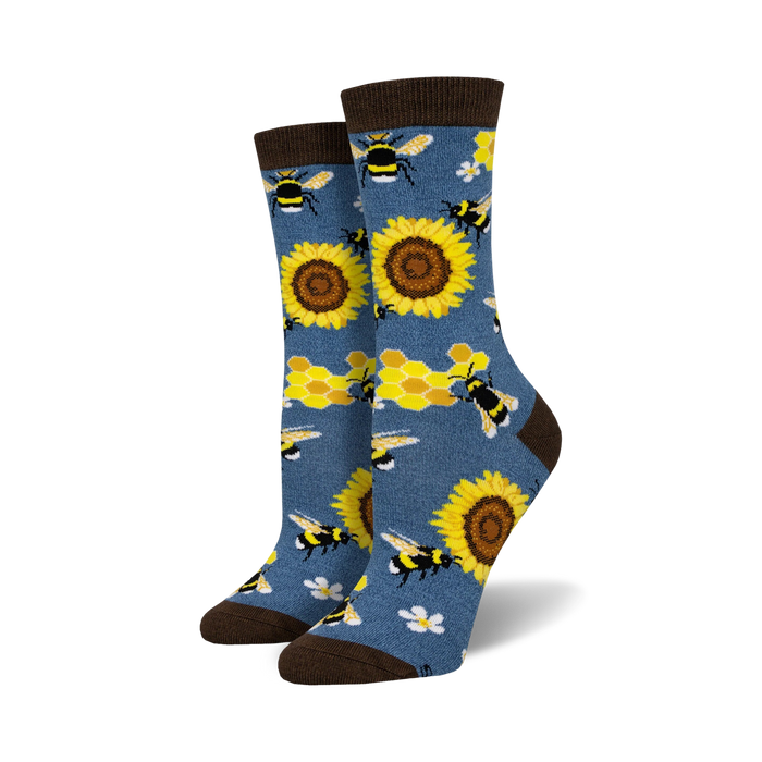 A pair of crew socks with bees, sunflowers and honeycomb pattern on a denim blue background. Brown top cuff.