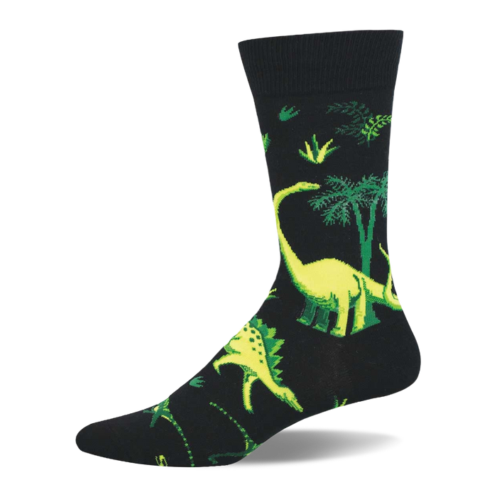 Black crew sock with vibrant yellow-green dinosaurs and green prehistoric trees/foliage. Long-necked and spiky dinosaurs visible. }}