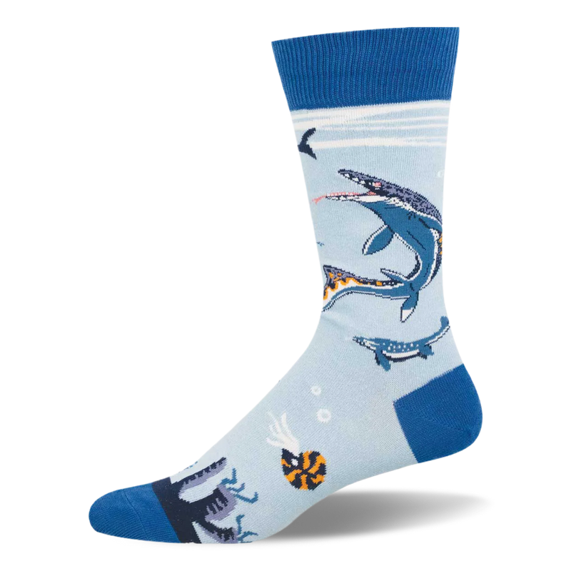 Light blue crew sock with dark blue heel, toe, and cuff. Features swimming Mosasaurus marine reptiles, an ammonite, and bubbles.
