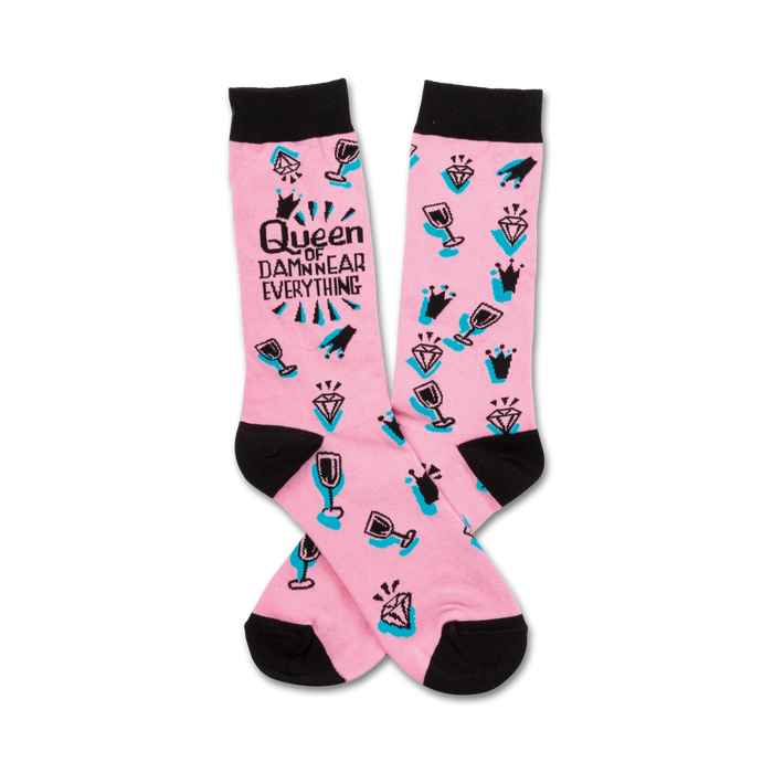 Pink crew socks with black toe and heel. Features a teal and black design of crowns, diamonds, wine glasses, and the text 'Queen of Damn Near Everything'. }}