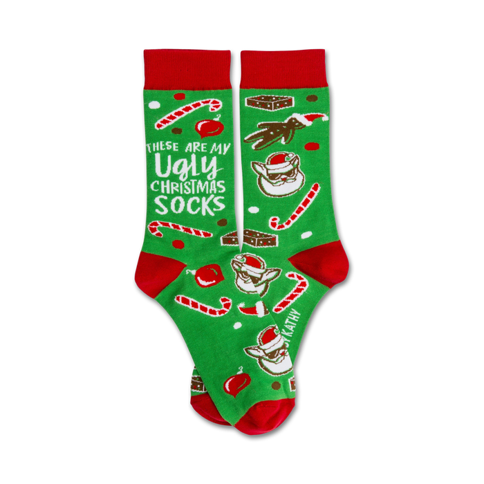 A pair of green crew socks with red cuffs. The socks are adorned with candy canes, brownies, and a funny Santa Claus design. The text 'These are my Ugly Christmas Socks' is featured. }}