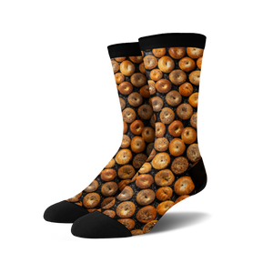 A pair of crew socks with a full-coverage print of various bagels in shades of brown and tan on a black background.