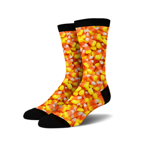 A pair of crew socks covered in a candy corn print. The socks are predominantly orange, yellow, and white, with a black cuff.