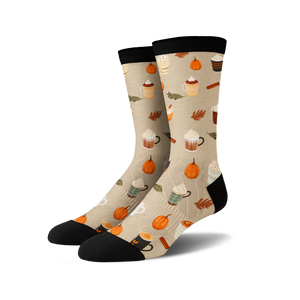 A pair of mid-calf socks with a pattern of coffee cups, pumpkins, and fall leaves on a beige background. The socks have black toes, heels, and cuffs.