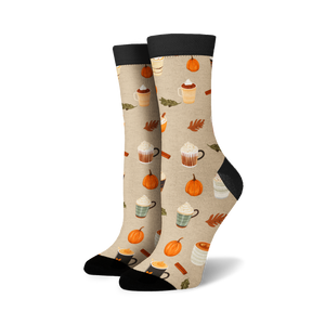 Pair of cream crew socks with a repeating pattern of pumpkins, coffee cups, and cinnamon sticks. Black cuffs.