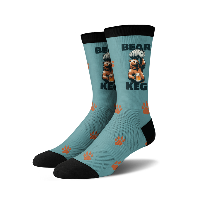 A pair of crew socks; teal blue with a brown bear lifting a keg of beer, orange paw prints, and black cuffs.