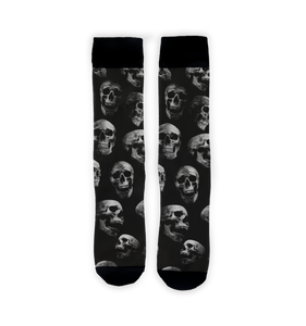 Flat lay showcasing a pair of black crew socks with a skull pattern.