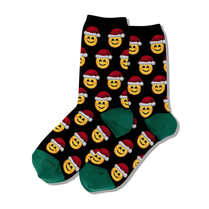 Pair of black crew socks.  Feature a repeating pattern of yellow smiley faces wearing red Santa hats. Green cuffs.