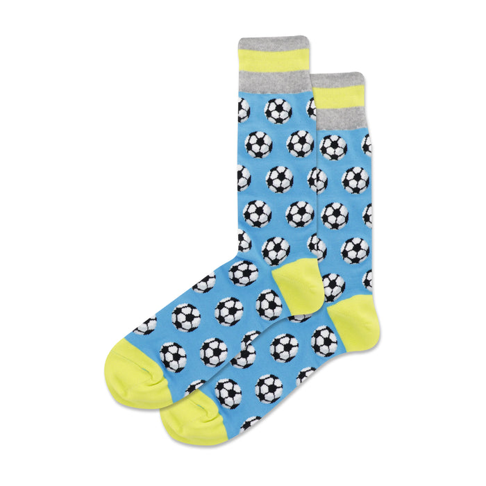 A pair of crew socks. The socks are light blue with a repeating pattern of black and white soccer balls. The cuffs have a grey and neon yellow stripe. }}